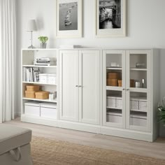 a living room with white furniture and pictures on the wall above it's bookshelf