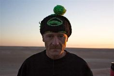 a man wearing a beanie with a green logo on it