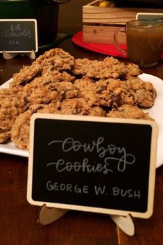 cookies are sitting on a plate with a chalkboard sign in front of them that says cowboy cookies george w bush