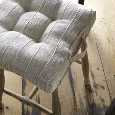 a wooden chair with a cushion on it sitting on top of a hard wood floor