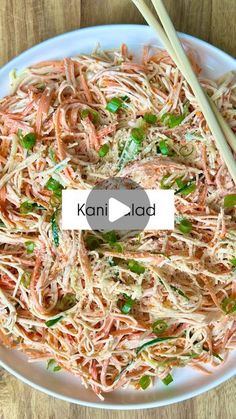 a white plate topped with noodles and chopsticks on top of a wooden table