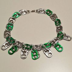 a green and silver bracelet with lots of metal handcuffs on the clasps that are attached to each other