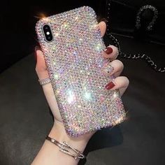 a woman's hand holding up a phone case with lots of diamonds on it