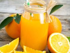 orange juice in a glass jar surrounded by sliced oranges and green leafy stems