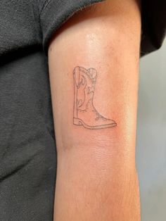 a tattoo on the arm of a person with a cowboy boot in front of them