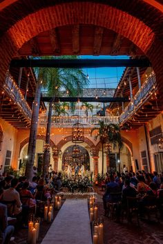 the inside of a building with candles lit up and people sitting at tables in it