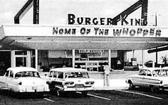 an old gas station with cars parked in front of it and the words burger king on the sign