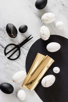 black and white eggs with gold foil next to them on a marble counter top,