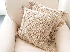 two crocheted pillows sitting on top of a white couch next to each other