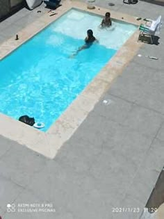 an aerial view of a swimming pool with people sitting in it and one person standing on the side