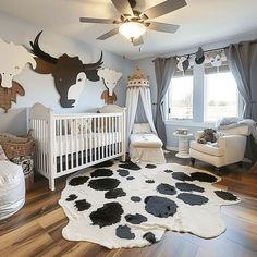 a baby's room decorated in white and black with cow prints on the wall