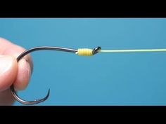 a person holding a fishing hook in their left hand with a yellow string attached to it