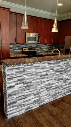 a kitchen with wooden flooring and granite counter tops on the island in front of stainless steel appliances