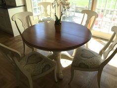 a dining room table with chairs and a vase filled with flowers sitting on top of it