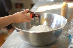 a person is mixing something in a bowl with an empty bottle on the table next to it