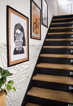 the stairs are decorated with black and white wallpaper, along with pictures on the wall