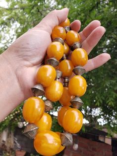 "Brilliant egg yolk yellow phenolic resin beads with metal spacers on this antique necklace, possibly Ethiopian. This type of resin bead, sometimes called African amber, was made of the same or similar materials as catalin (the jewelry form of bakelite). Each bead is approximately .75\" wide x .9\" long. I don't know what the metal spacers beads are made of. As found, necklace cord is quite stretched out. Total weight is approximately 200g (7 ounces), length is approximately 32\", 21 resin beads Vintage Polished Yellow Beads Jewelry, Vintage Orange Wooden Beads, Handmade Round Bakelite Jewelry, Vintage Yellow Jewelry With Polished Beads, Vintage Yellow Jewelry With Large Beads, Vintage Yellow Polished Beads, Vintage Orange Necklace With Wooden Beads, Vintage Amber Resin Jewelry, Vintage Yellow Resin Jewelry