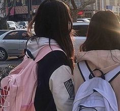 two girls walking down the street with backpacks on