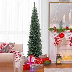 a cat sitting on a couch next to a christmas tree in front of a fireplace