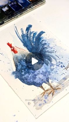 a painting of a blue bird on a white table next to some paintbrushes