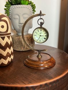 a clock sitting on top of a wooden table next to a potted succulent