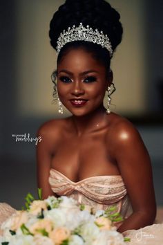 a woman in a dress and tiara sitting on a bed with her wedding bouquet