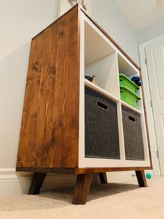 a wooden cabinet with two bins on top of it in a room next to a door