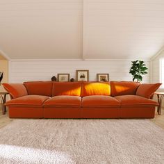 an orange couch sitting in the middle of a living room next to a white rug