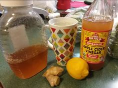 the ingredients for an apple cider vinegar drink are displayed on a counter with two mugs