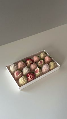 a box filled with assorted chocolates on top of a white table next to a wall