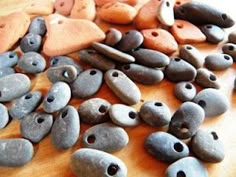 some rocks are laying on a wooden table and one has holes in the middle to make them look like they have eyes