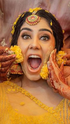 a woman with her face painted yellow and holding hands up to her mouth as she looks surprised