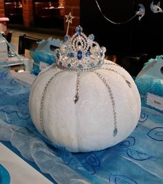 a white pumpkin with a tiara on it sitting on a blue and white table cloth