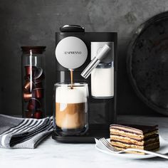 an espresso machine with milk being poured into it next to slices of cake