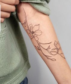 a woman's arm with a flower tattoo on the left side of her arm