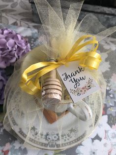 a wine bottle wrapped in tulle and tied with a yellow ribbon, sitting on top of a glass plate