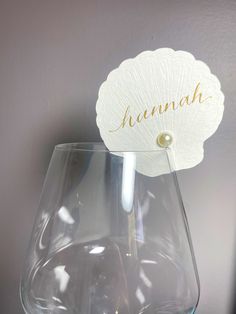 a wine glass with a name on it sitting on a table next to a wall