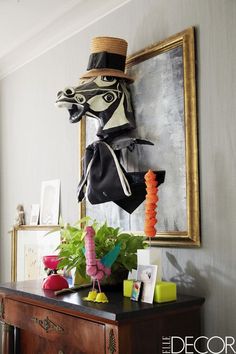 an image of a horse head hanging on the wall above a table with books and other items