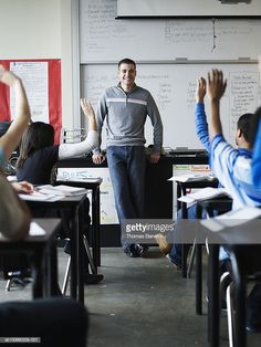 a man standing in front of a class room full of students with their hands up