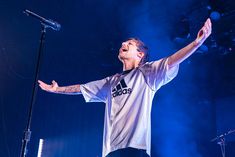 a man standing on top of a stage holding his arms up in the air while singing into a microphone