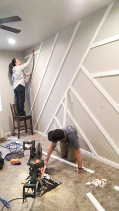 two men working on an unfinished wall in a room that is being remodeled with white paint