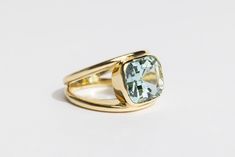 a yellow gold ring with an aqua blue topazte stone in the center on a white background