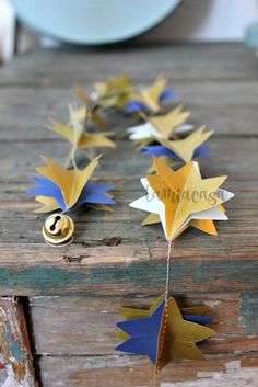 some gold and blue paper stars are hanging from a string on an old wooden table