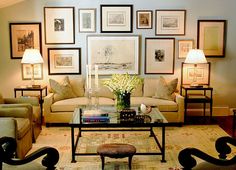 a living room filled with furniture and framed pictures on the wall above it's coffee table