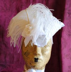 This quite theatrical bridal baroque mini tricorn hat is covered with a stunning white brocade.It is embellished with a glorious white ostrich feather, white roses and white bows! The edge of the brim is trimmed with pleated ribbon and braided trimming, creating a sculptural effect. This mini hat is fully lined with satin. It has both a thin elastic that you can wear it under your hair, to achieve stability and that perfect angled look, as well as satin ribbons that tie under the chin. Measureme 18th Century Hats, Mardi Gras Hats, Bridal Mini, Tricorn Hat, Mini Hat, Bridal Hat, Pirate Hats, Costume Hats, Ostrich Feathers