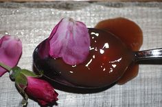 a spoon filled with liquid next to pink flowers