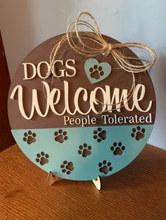 a wooden sign that says dogs welcome people tolerrated and has paw prints on it