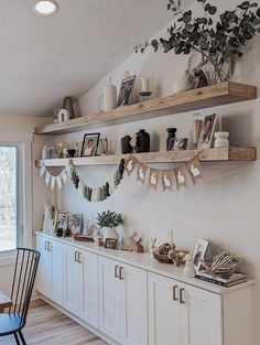 a kitchen with white cabinets and wooden shelves filled with items on top of each shelf