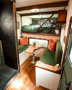 the inside of a small camper with green couches and wood flooring in it