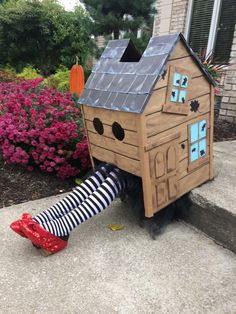 a child's legs sticking out from under a cardboard house with windows and doors